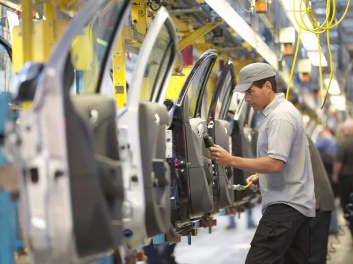 A worker examines car doors on a production assembly line.