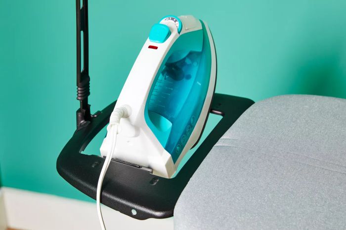 An iron resting on the plastic holder of the Bartnelli Heavy Duty Ironing Board.
