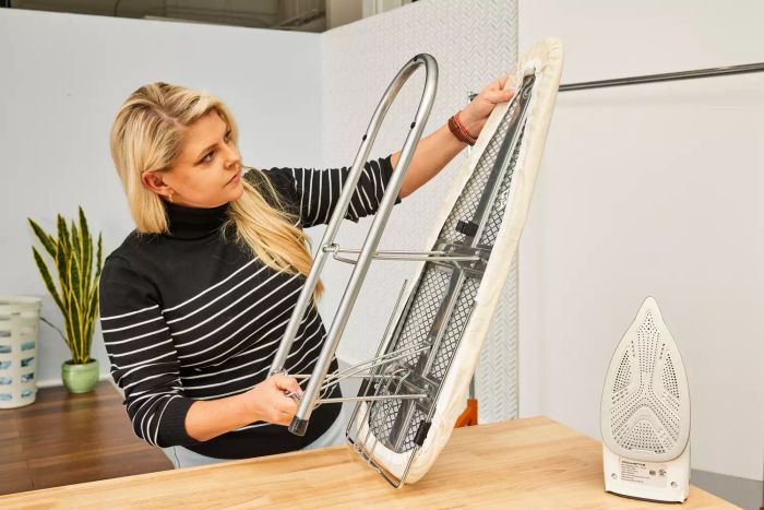 A person unfolding the Household Essentials 131210 Small Steel Table Top Ironing Board to begin ironing.