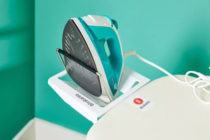 An iron placed on the Brabantia Size B Ironing Board's iron holder, ready for use.