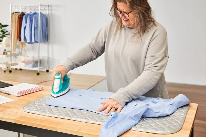 A person ironing a shirt using the BNYD Portable Ironing Mat Blanket