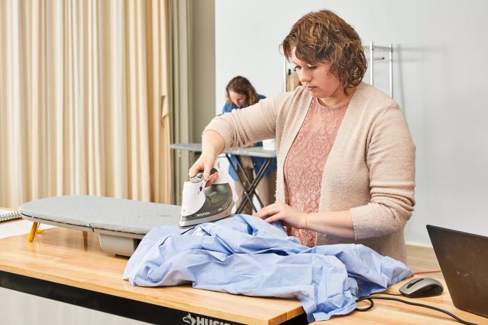 A person ironing a shirt using the Joseph Joseph Pocket Folding Ironing Board