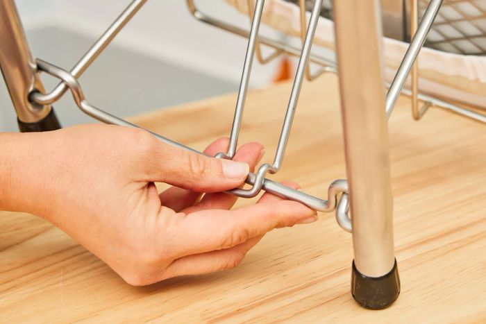 A person assembling the Household Essentials 131210 Small Steel Table Top Ironing Board, readying it for use.