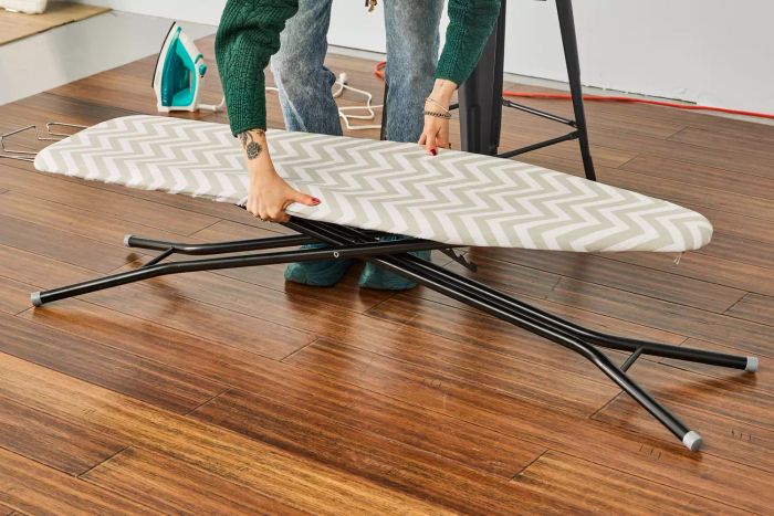 A person assembling the Amazon Basics Full-Size Ironing Board by lifting it into place.