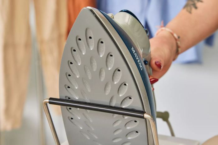 A hand gripping an iron on the Brabantia Size B Ironing Board, demonstrating ease of use.