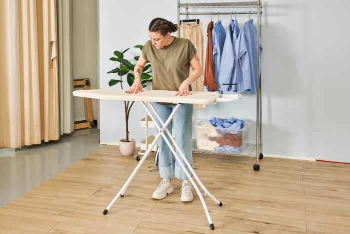 A person ironing on the Brabantia Size B Ironing Board, pressing down on its surface.