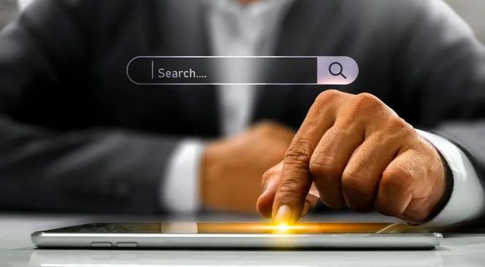 A hand interacts with a tablet, displaying a search bar on the screen.
