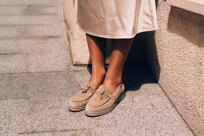 Stylish women dressed in beige outfits and chic suede loafers posing elegantly on a city street