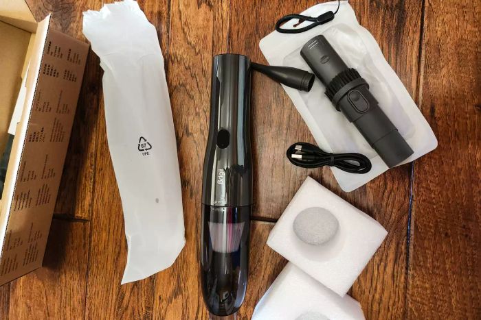 An unassembled Brigii M5 Cordless Crevice Vacuum placed on a wooden floor