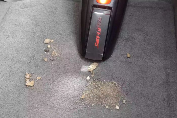 The ArmorAll Armor All-12V Wet/Dry Car Vac (AA12V10901) in action, removing dirt from a car interior