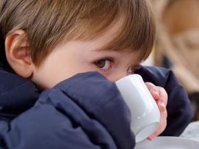 A young child sipping on a warm drink.