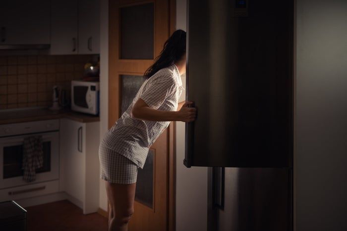 A person staring into an open fridge