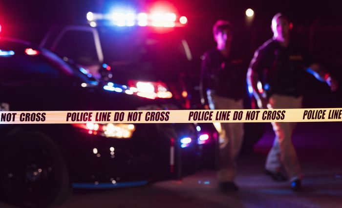 A police vehicle with flashing lights and yellow caution tape blocking the area