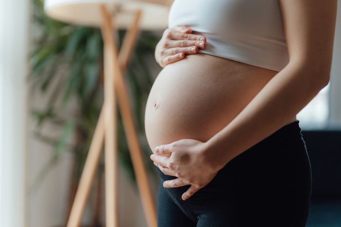 A pregnant woman cradling her belly gently