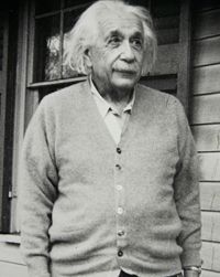 A monochrome photograph of Albert Einstein wearing a cardigan.