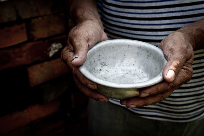 A person holding an empty bowl outstretched