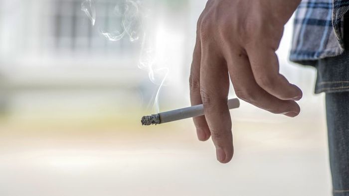A person holding a lit cigarette.