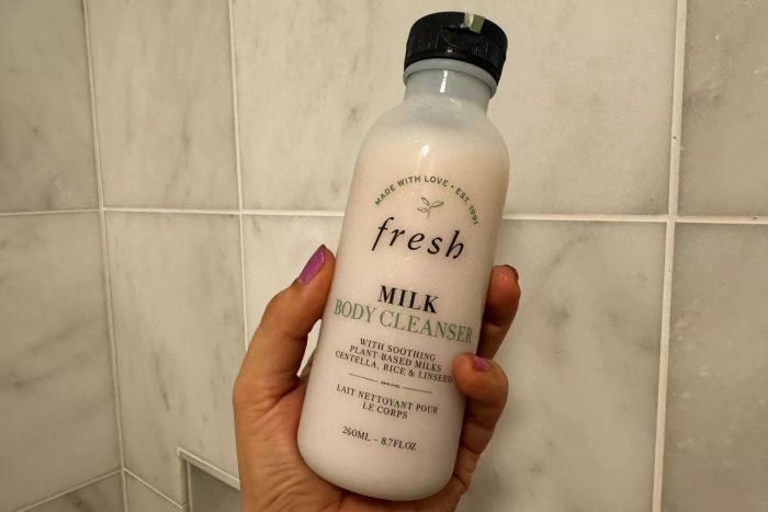 A bottle of fresh Milk Body Cleanser held in someone's hand