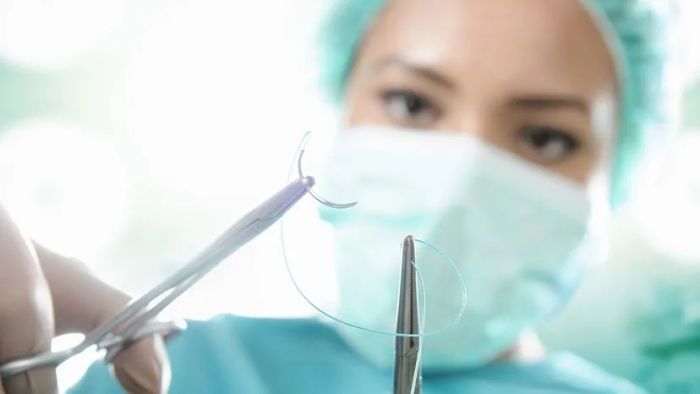 A surgeon suturing a patient.
