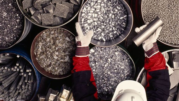 A worker organizes containers filled with metals and ores, preparing them for various industrial uses.