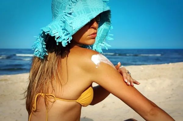 A woman applies sunscreen at the beach