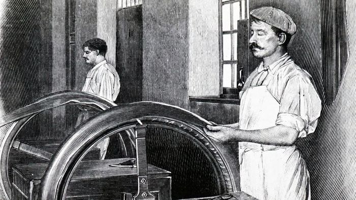 Workers apply rubber layers onto a canvas base