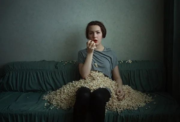 A depressed girl munches on popcorn