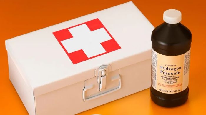 A bottle of hydrogen peroxide next to a sealed first aid kit.
