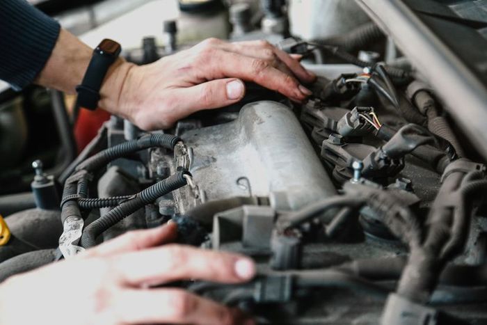 Two hands interact with an engine surrounded by metallic components