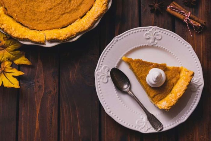 An overhead shot of a slice of pumpkin pie placed on a table.