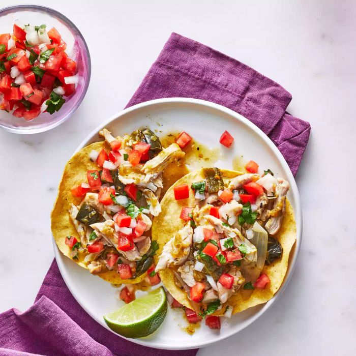 Slow-cooker Chicken Tostadas with toppings on a white plate with a purple cloth napkin