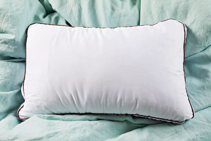 The Saatva Latex Pillow showcased on a green comforter