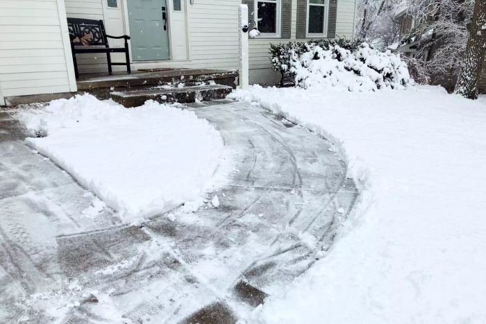 A snow blower has cleared a path in front of a house.