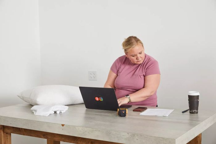 A person working on a laptop beside the Nest Bedding Easy Breather Natural Pillow showcased on a table