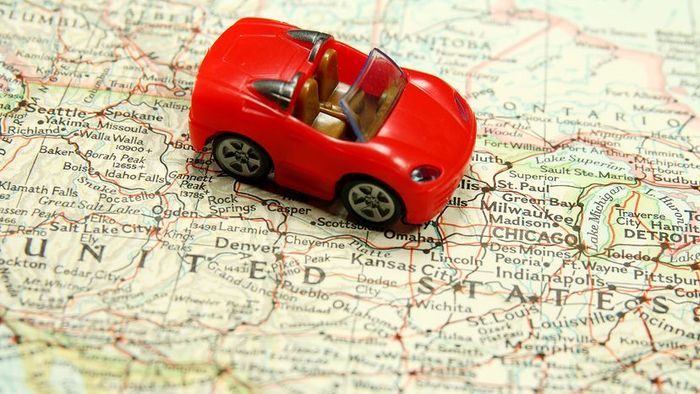 A red toy car placed on a map of the United States.