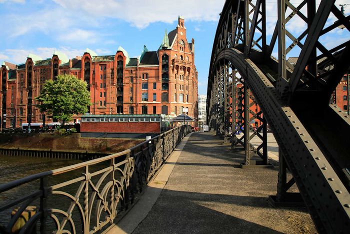 A picturesque bridge spanning a canal, offering a scenic view of distant red brick buildings.