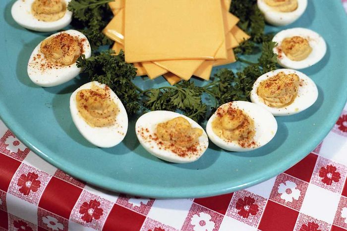 Deviled eggs arranged on a blue plate with parsley garnishes and Kraft singles.