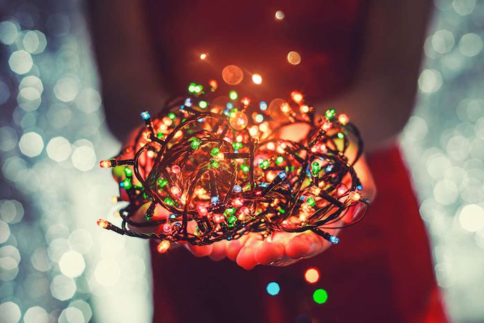 A person holding a bundle of illuminated Christmas lights