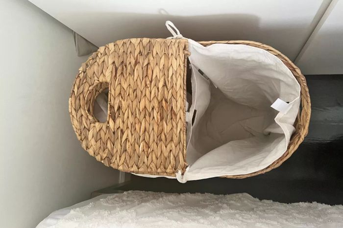 A top-down view of the Seville Classics Woven Laundry Hamper, half open on the floor.