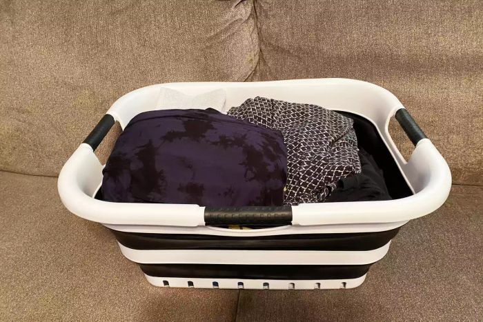 Sammart Collapsible Laundry Basket 2-Pack placed on the couch, holding clothes