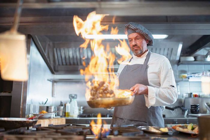 A chef cooking with flames in the kitchen.