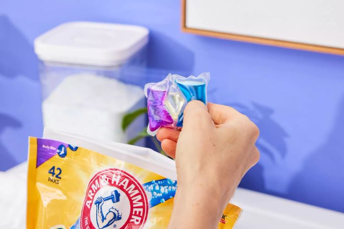 A person is holding Arm & Hammer Plus OxiClean Odor Blasters 5-In-1 Power Paks pods