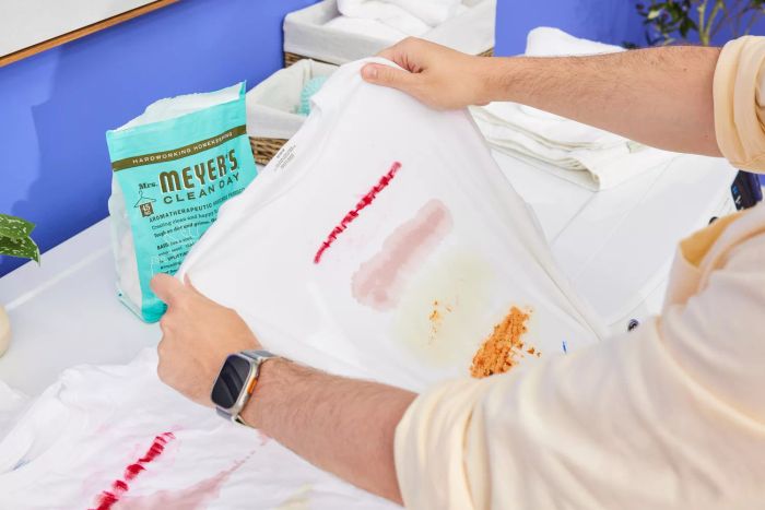A person is holding a dirty cloth, preparing to wash it with Mrs. Meyer’s Clean Day Laundry Detergent Pacs.