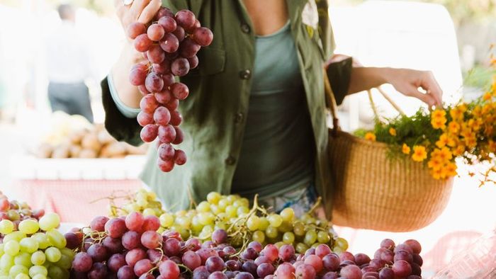 A woman shopping for grapes at a market.