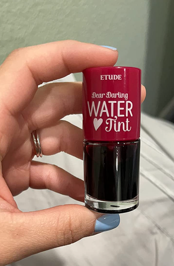 Reviewer holding the red version of Dear Darling Lip Tint in their hand