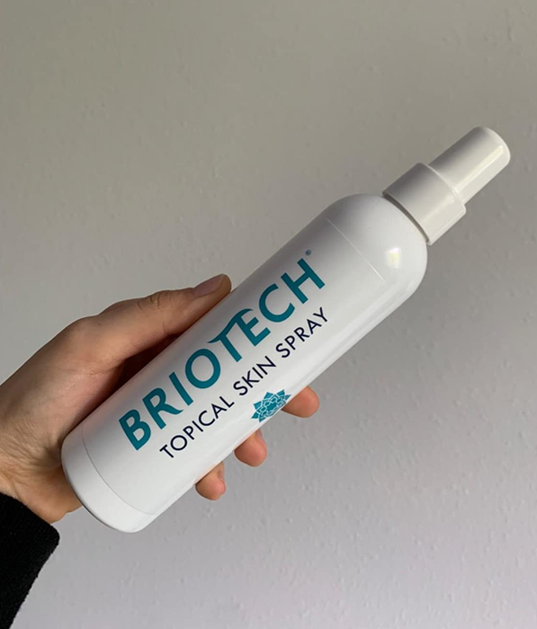 A reviewer holding their Briotech spray bottle in hand