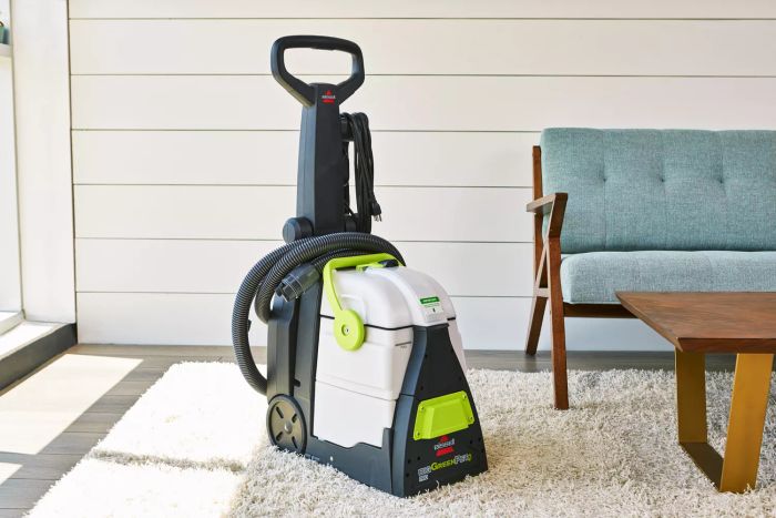 The Bissell Big Green Pet Pro Carpet Cleaner is shown positioned beside a sofa and a coffee table.