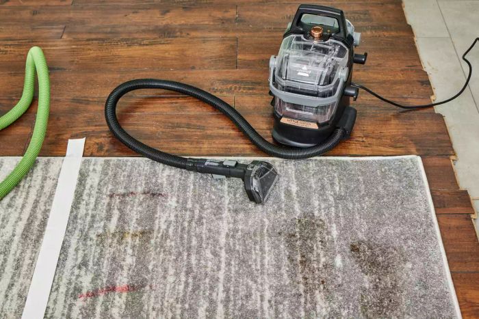 The Bissell Little Green HydroSteam Pet Carpet Cleaner placed on a soiled carpet square.