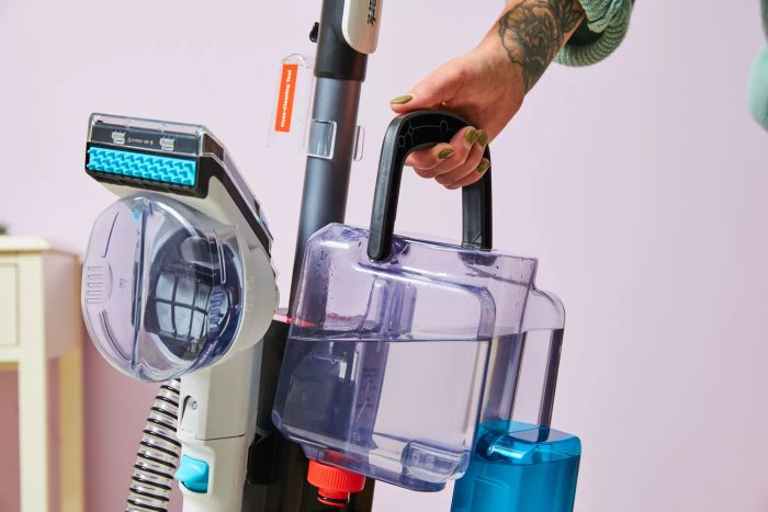 A person grips the handle of the Shark CarpetXpert with Stainstrike Upright Deep Carpet Cleaner