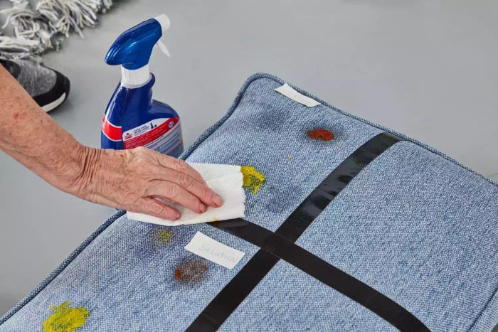 A person dabbing stains on a cushion using a paper towel
